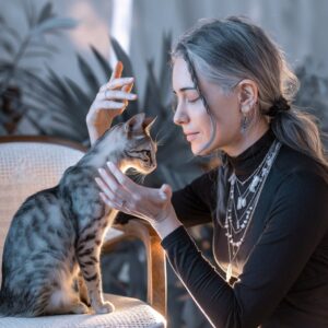 Eine Katze sitzt einer Frau gegenüber, beide haben die Augen geschlossen und die Frau legt ihre Hände beschwörend über den Kopf der Katze. Welche spirituelle Bedeutung hat die Bauchspeicheldrüse?